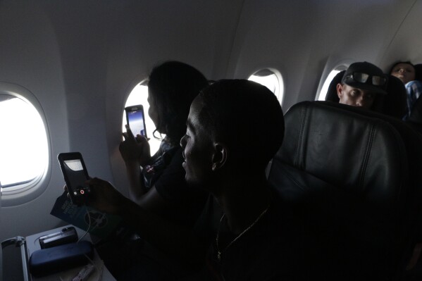 Jasmine Shepherd, at window, and her brother Joshua, take photos from their seats on a special eclipse chaser flight before the flight intercepted a total solar eclipse, on Monday, Aug. 21, 2017, over the Pacific Ocean. Passengers witnessed totality from over the ocean. (AP Photo/Rachel La Corte)